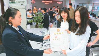 河北省承德市網(wǎng)絡(luò)代購經(jīng)營者陳晨(右)從工作人員手中接過帶有統(tǒng)一社會信用代碼的營業(yè)執(zhí)照。 劉環(huán)宇攝(人民圖片)