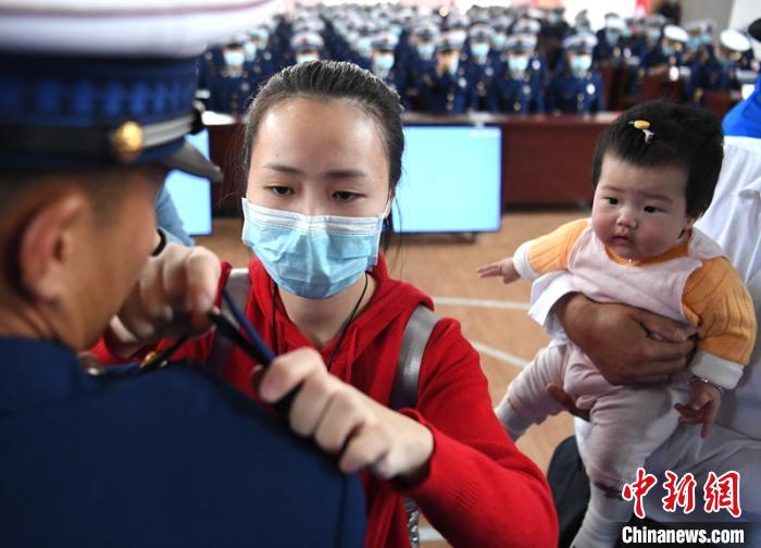 新消防員楊振的妻子彭莉與女兒現(xiàn)場見證丈夫加入“火焰藍(lán)”的神圣時(shí)刻?！⒅铱?攝