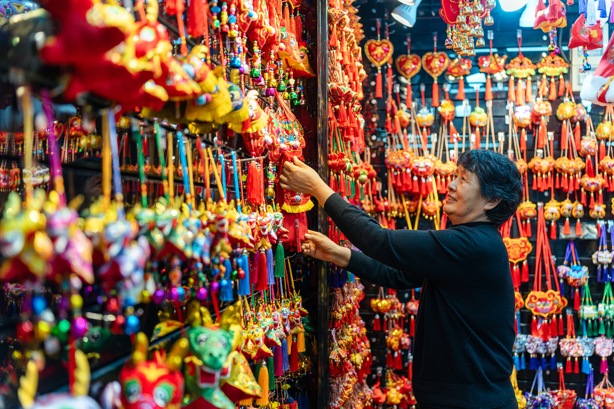 2023年12月11日，金華義烏國際商貿城，龍年喜慶用品掛滿攤位，顧客正在挑選中。